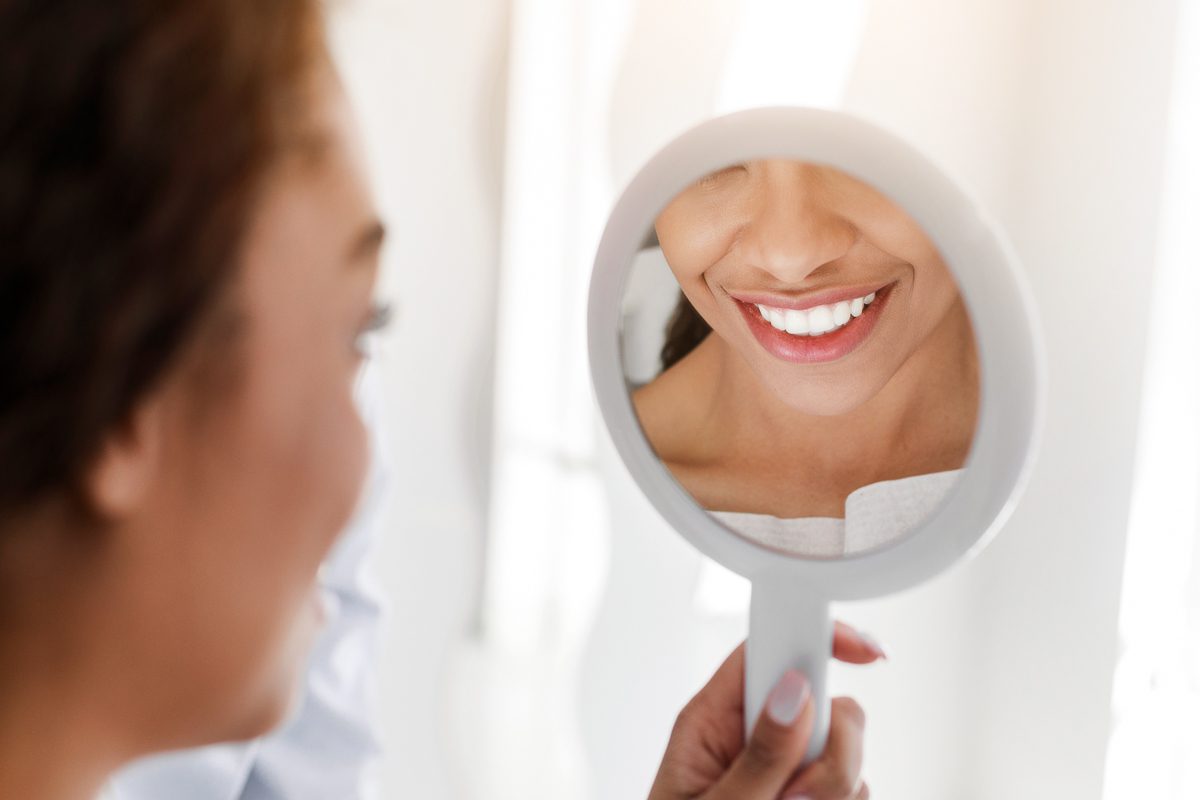 Woman admiring her bright smile after professional teeth whitening - SoBro Dental